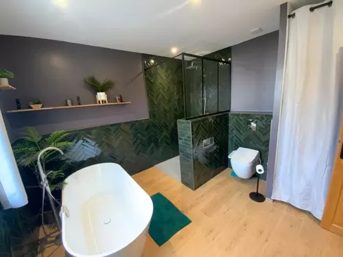 Salle de bain rénovée : douche à l’italienne en carrelage vert et sol parquet