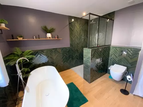 Salle de bain : douche vitrée carrelée en vert et baignoire îlot